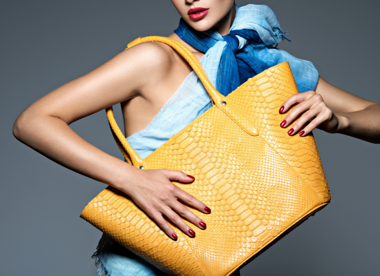 A woman holding a yellow luxury fashion brands bag